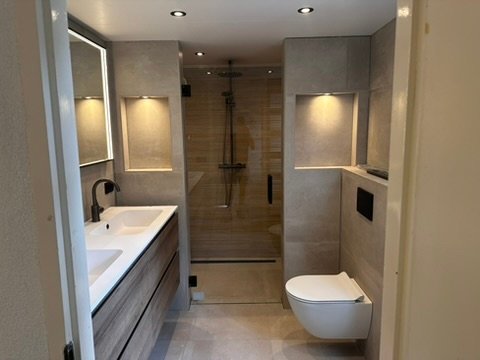 Luxe badkamer met houtlook vloer en wandtegels in een woning in Zuidhorn.