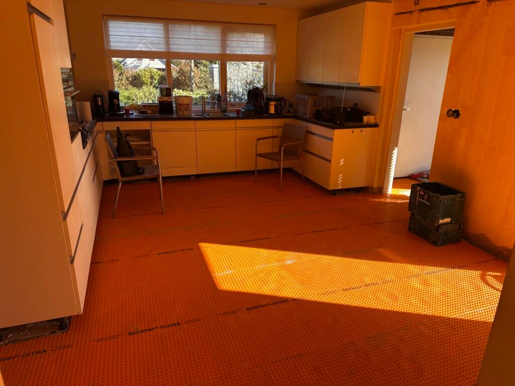 Aanbrengen Schlüter-DITRA ontkoppelingsmat op vloer in Kropswolde ter preventie van scheuren door aardbevingen.